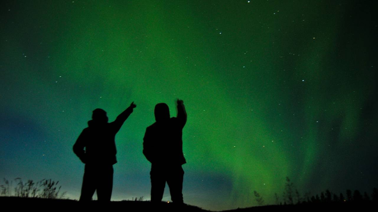 Two people looking up at the northern lights