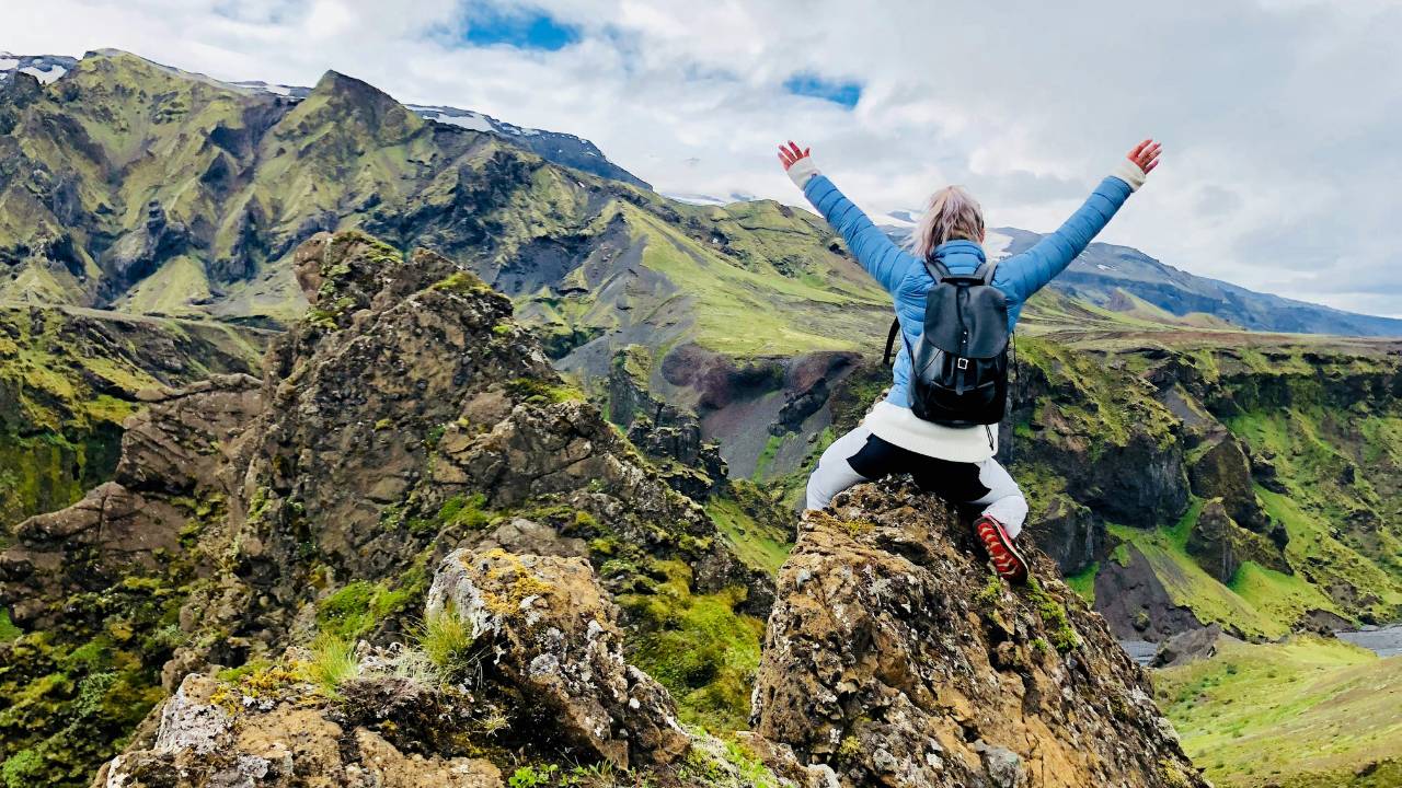 A woman celebrating climbing up a mountain 